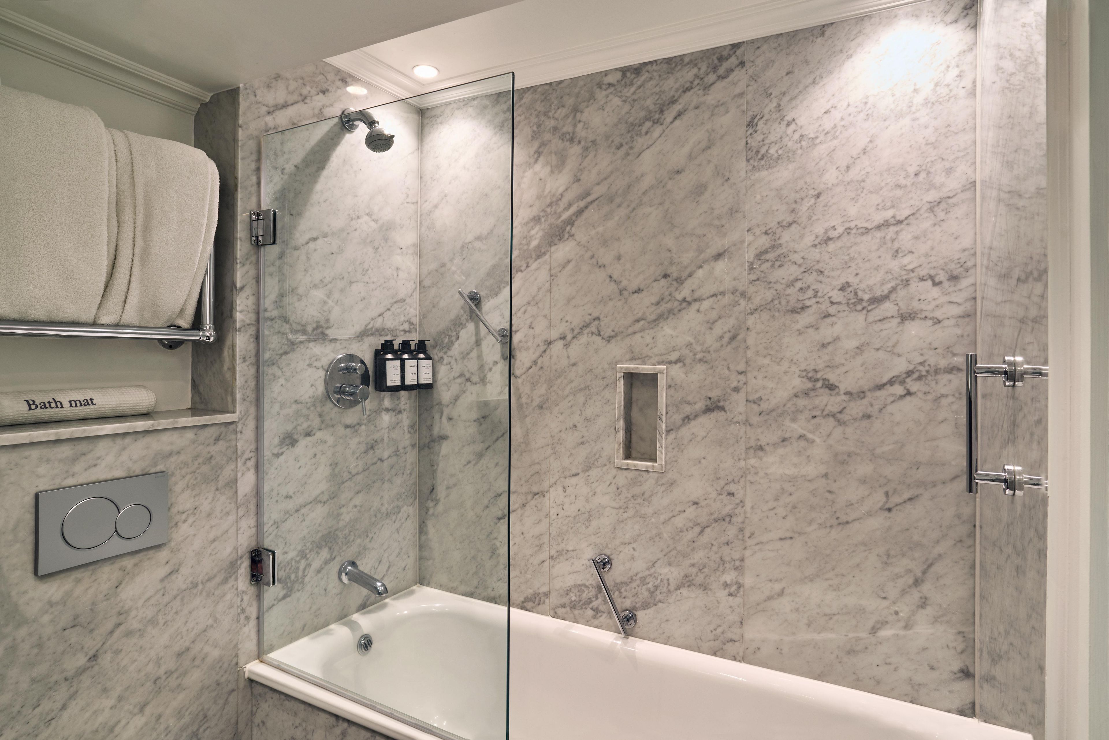 Une salle de bain moderne avec une douche à parois de verre, une baignoire et un mur en marbre.