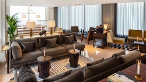 Una sala de estar moderna con sofá, sillones, una mesa de centro y una mesita de noche con una vela.