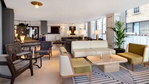 A modern living room with a sofa, armchairs, a coffee table, and a dining area with a glass table and chairs. - Radisson Blu Hotel, London Bond Street (London)