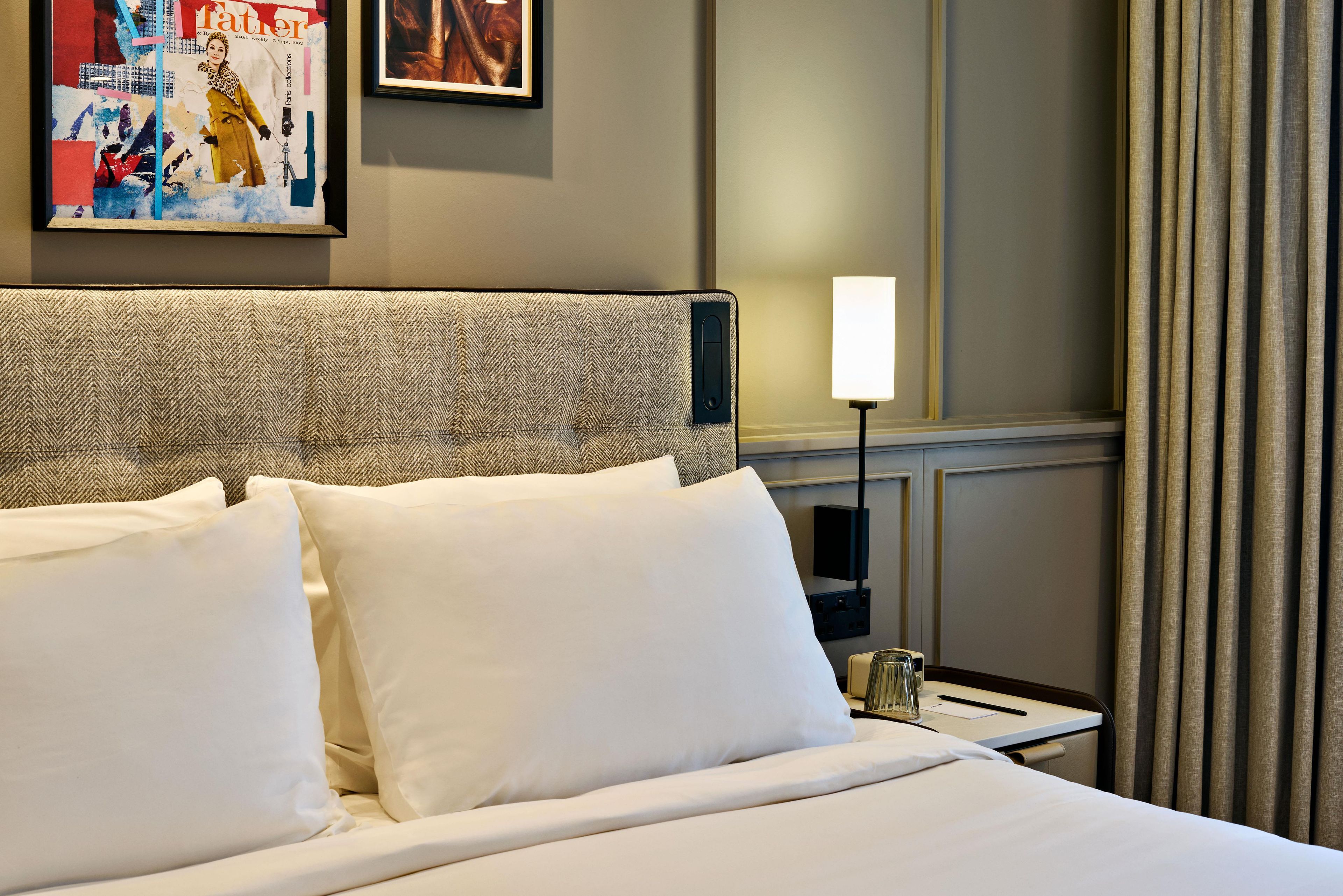 A hotel room with a large bed, a nightstand with a lamp, and a wall-mounted TV.