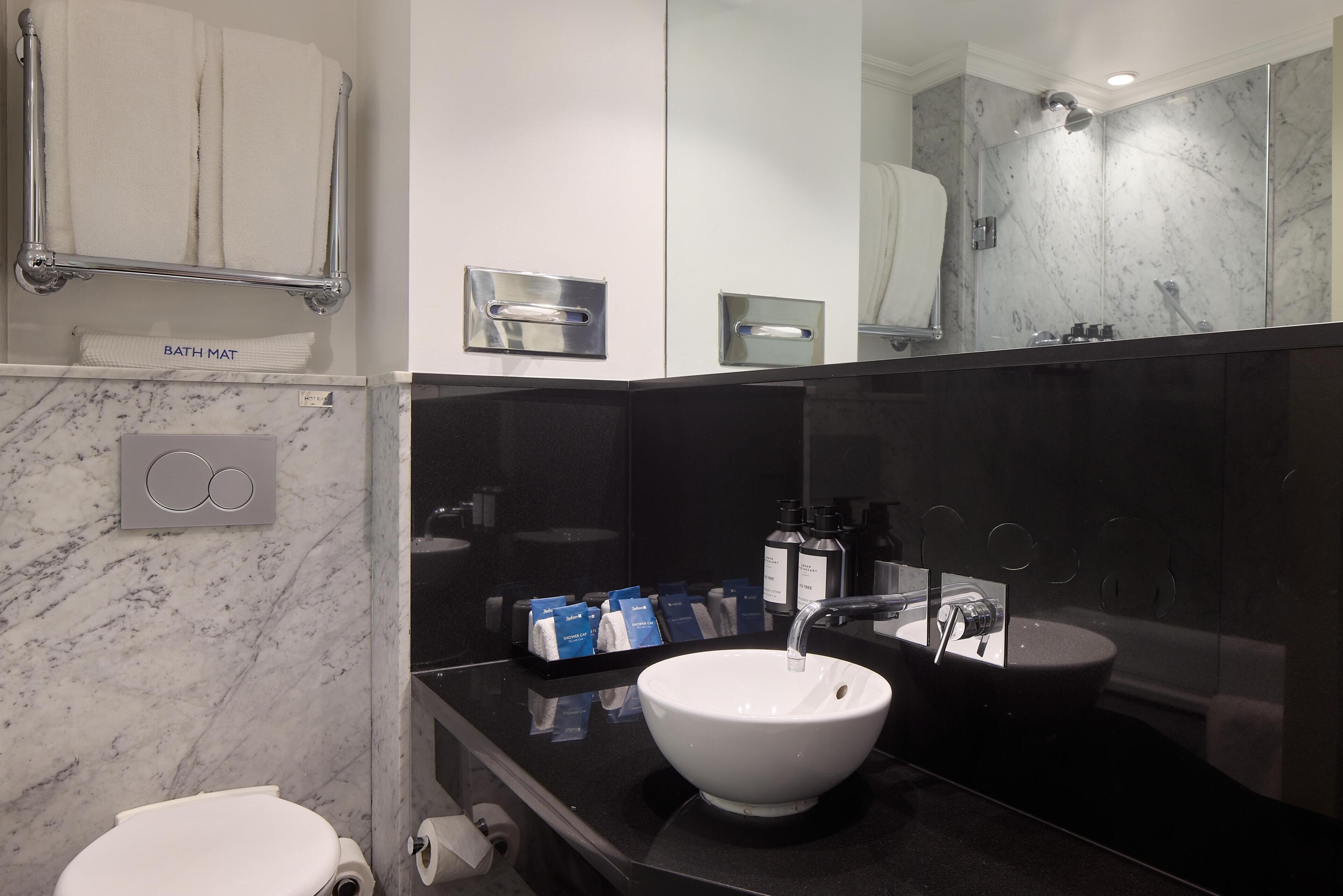 A modern bathroom with a white toilet, a white sink, a towel rack, and a mirror.