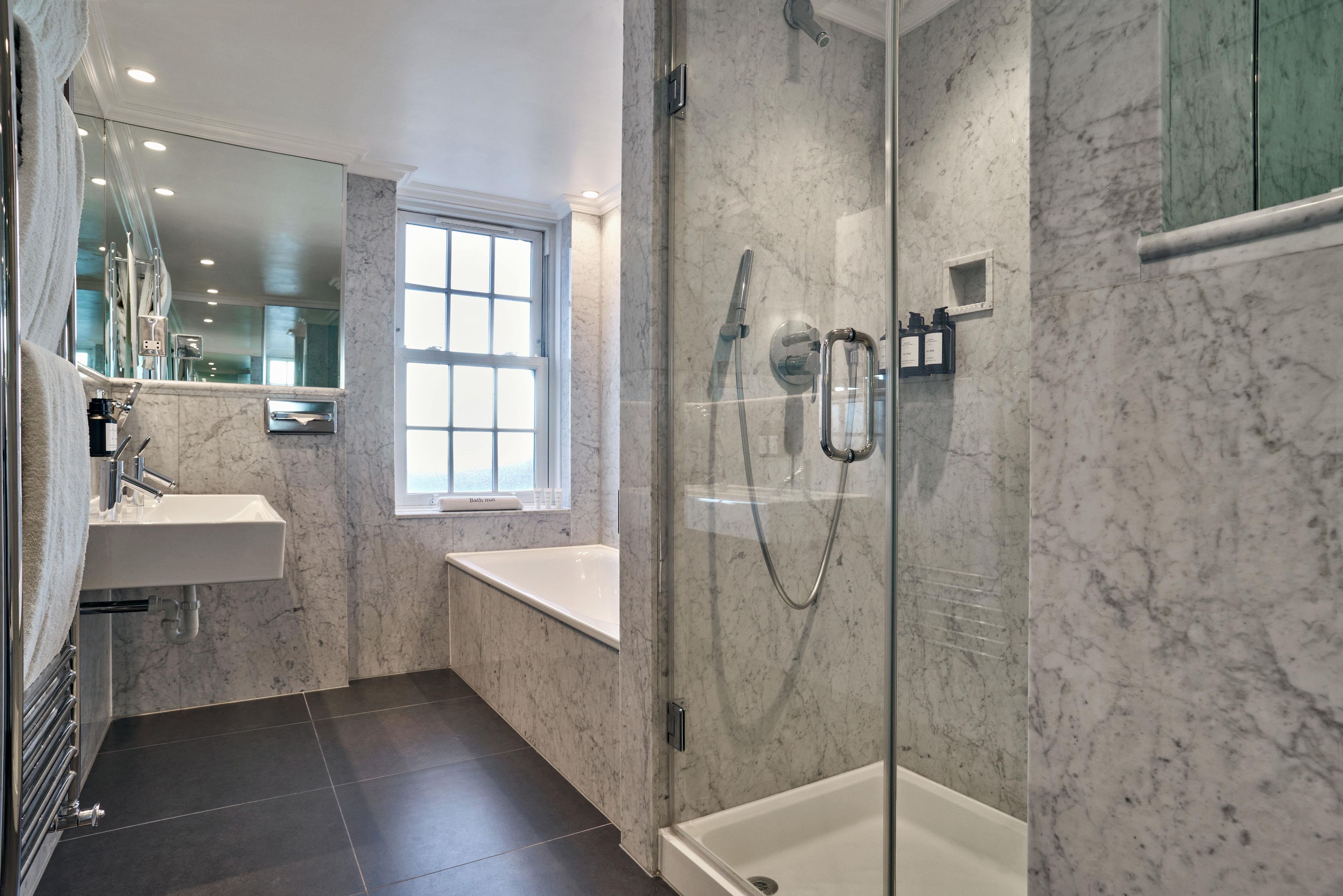 A modern bathroom with a glass-enclosed shower, a bathtub, and a sink.