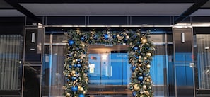 A modern building entrance with a glass facade and a Christmas tree adorned with blue and gold ornaments. - Radisson Blu Hotel, London Bond Street (London)