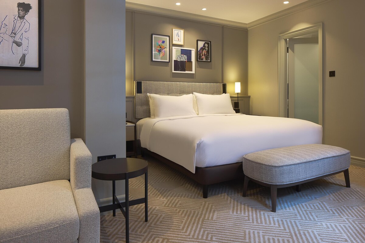 Una habitación de hotel con una cama, un sofá, una mesita y un banco.