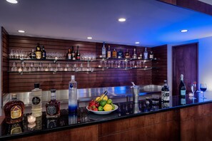 A bar area with shelves of liquor bottles, glasses, and a bowl of fruit. - Doubletree by Hilton Philadelphia Airport (Philadelphia)