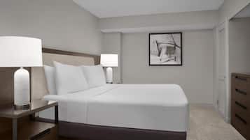 A hotel room with a large bed, two bedside tables with lamps, a framed artwork on the wall, and a wardrobe.