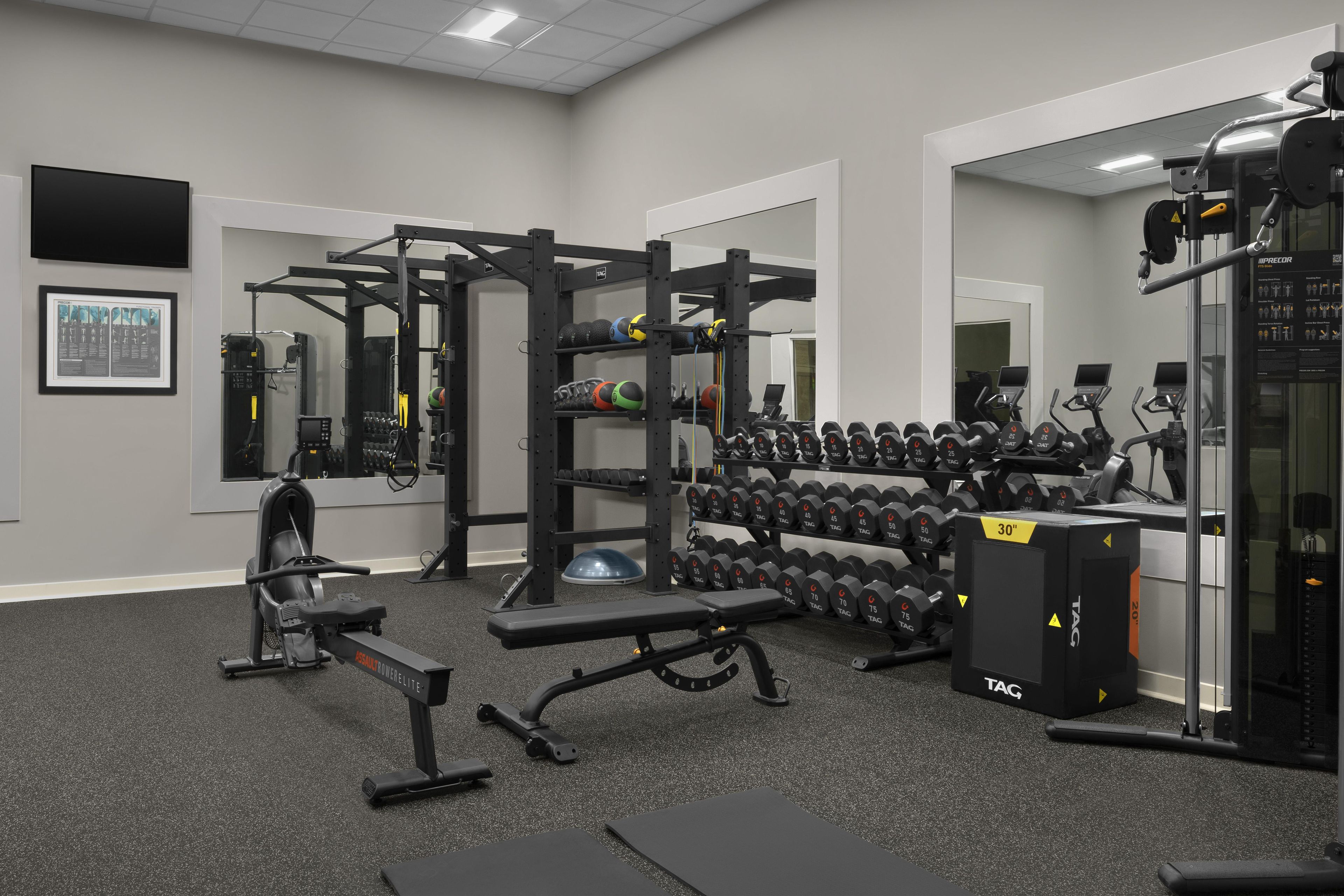 A gym with weightlifting equipment, dumbbells, and exercise machines.