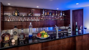 A bar area with shelves of liquor bottles and glasses, a bowl of fruit, and a bar counter. - Doubletree by Hilton Philadelphia Airport (Philadelphia)