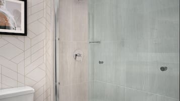 Un baño con ducha, inodoro y un cuadro en la pared.