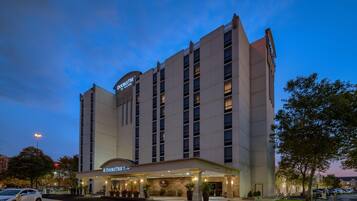 A hotel with a prominent 'DoubleTree by Hilton' sign, a covered entrance, and a parking lot.