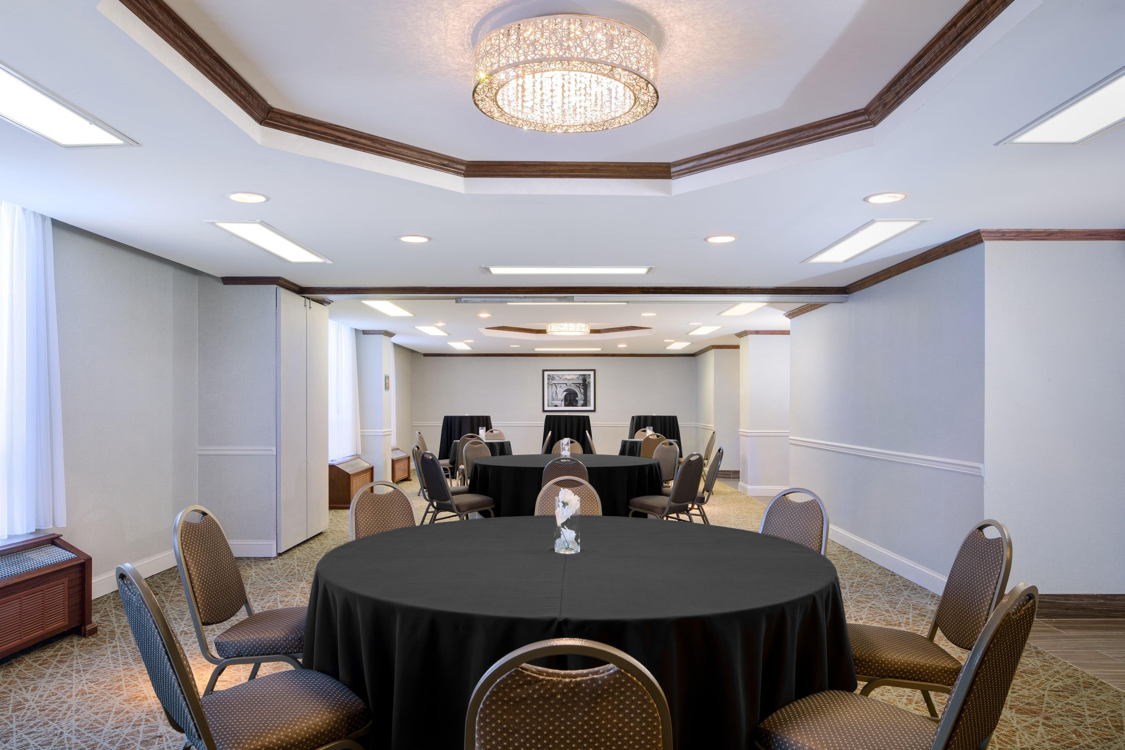 A conference room with a round table, chairs, and a chandelier.