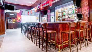 A bar area with multiple stools and a counter with a display screen.