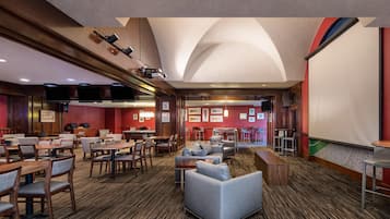 Un vestíbulo de hotel con varias zonas de estar, una mesa de billar y un bar.