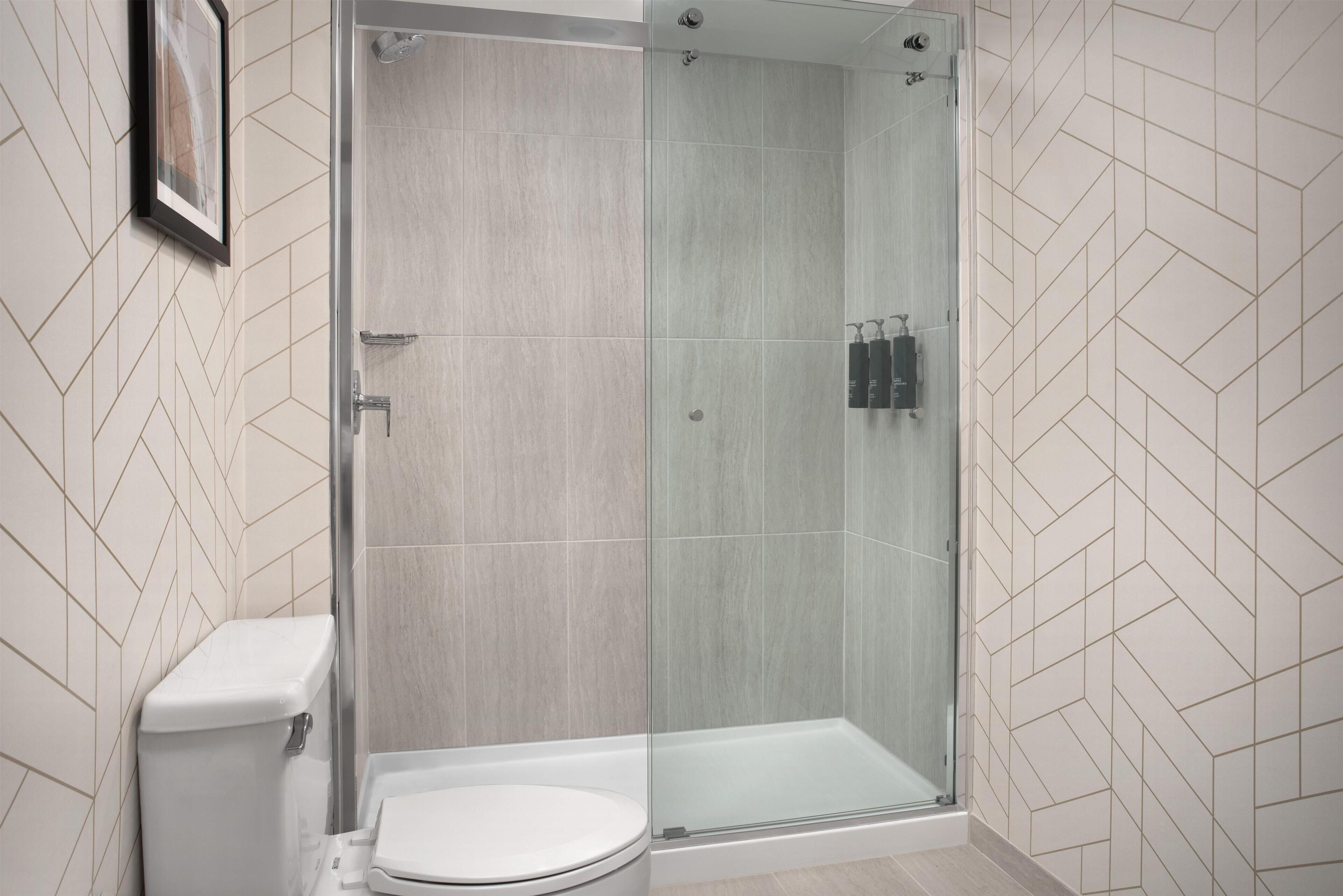 A modern bathroom with a glass-enclosed shower, a toilet, and a sink.