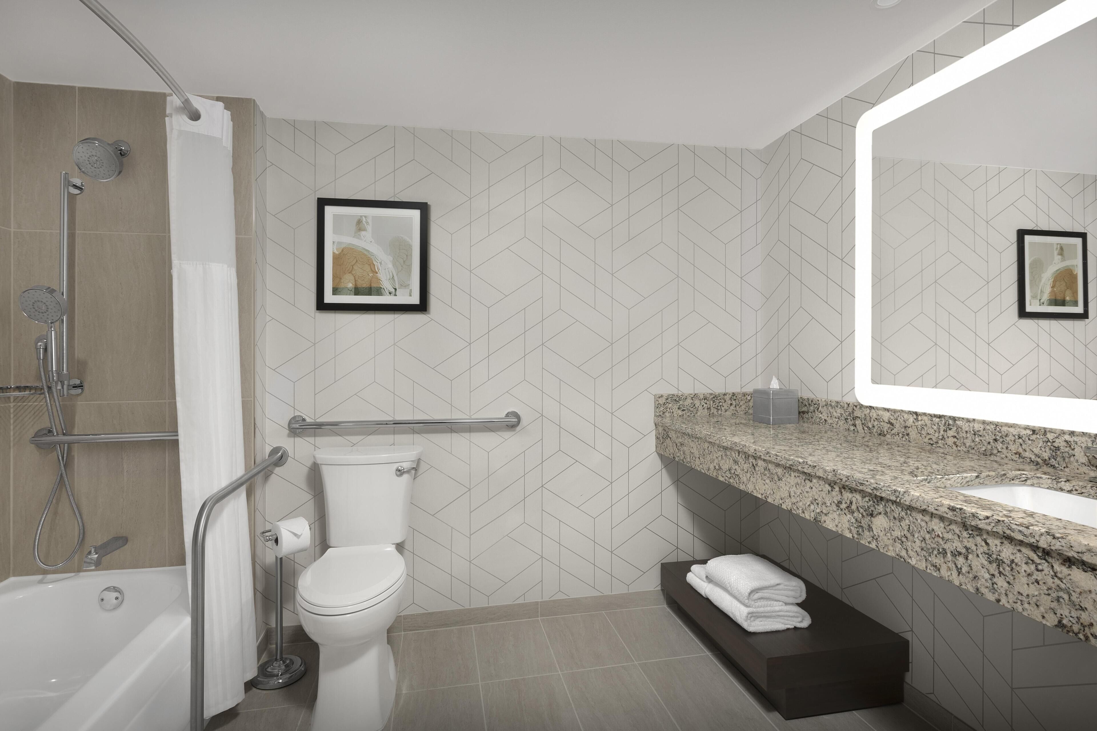 Une salle de bain moderne équipée d’une douche, de toilettes, d’un meuble-lavabo et d’un grand miroir.