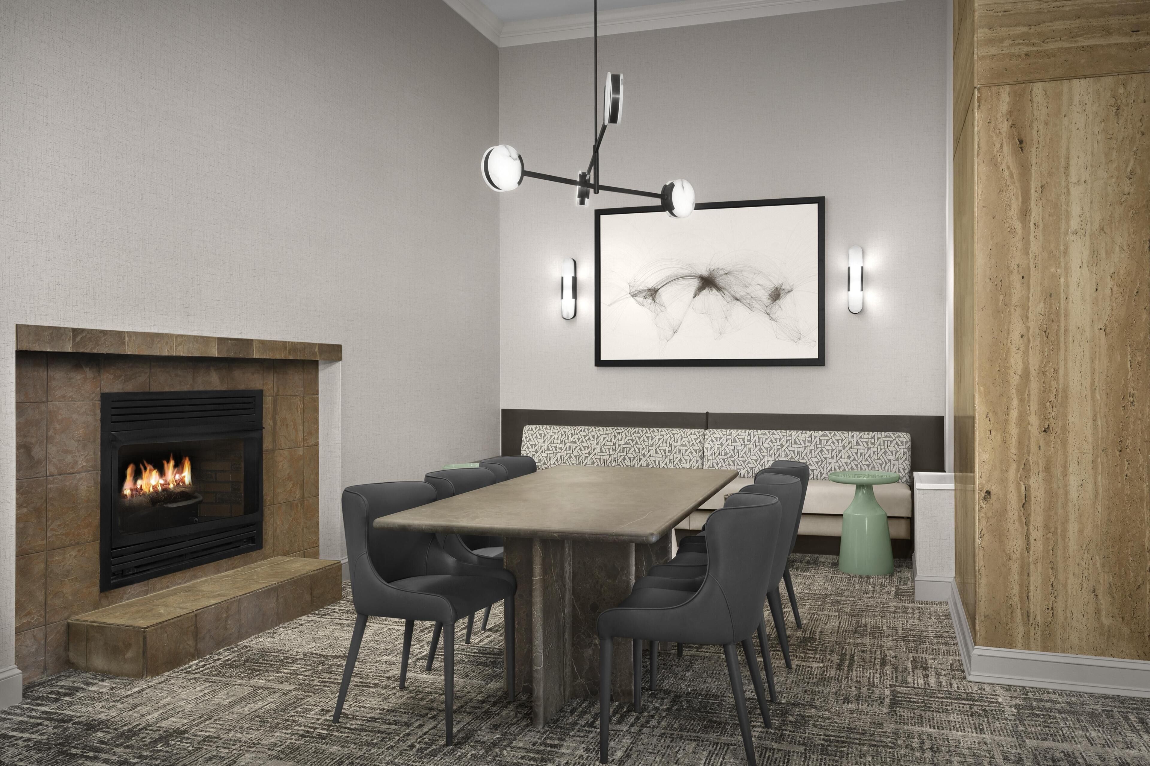 A modern dining area with a fireplace, a wooden table, and black chairs.