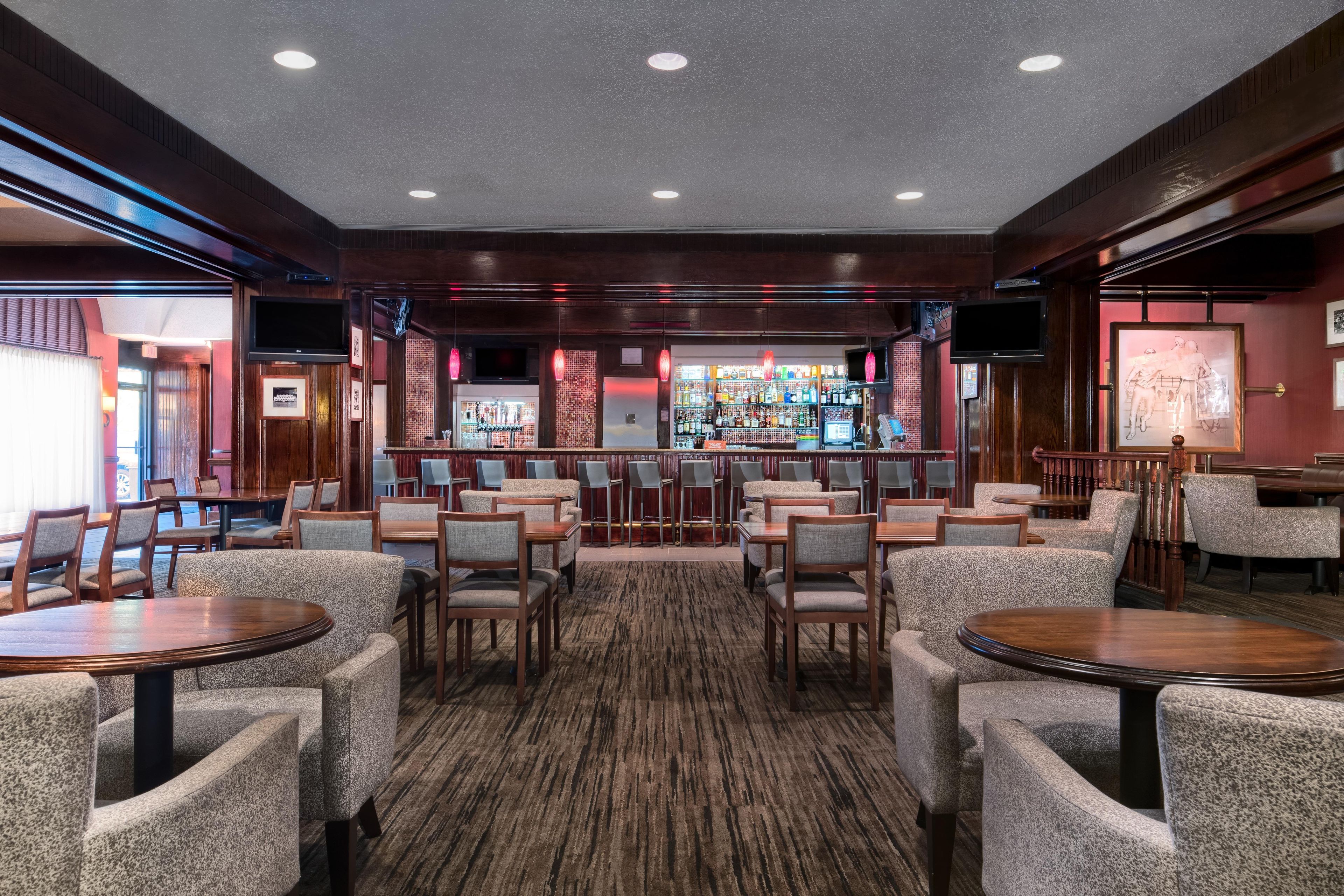 A bar area with seating, a bar counter, and a television screen.
