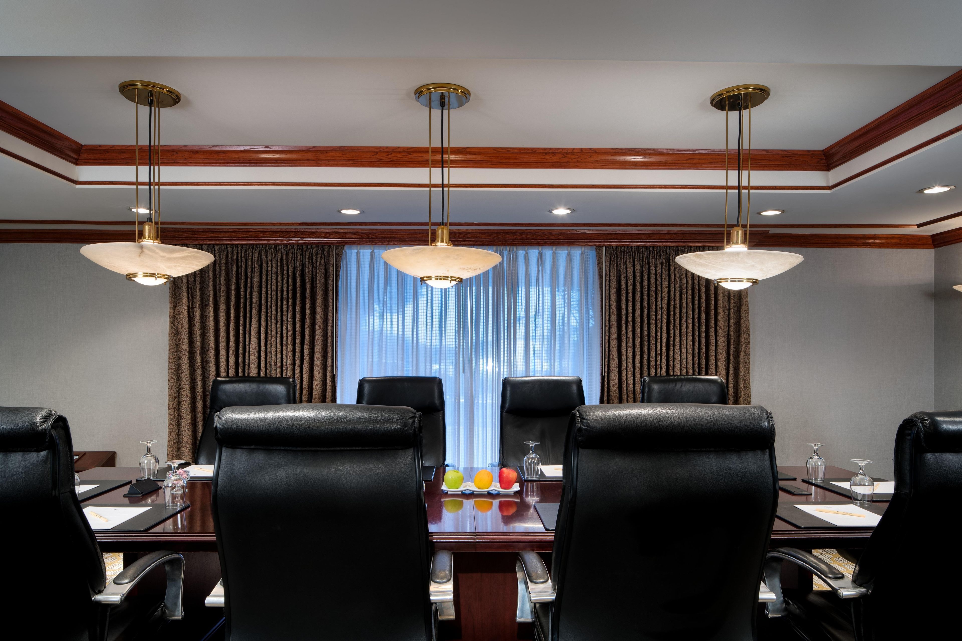 A conference room with a long table, black leather chairs, and pendant lighting.