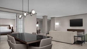 A hotel room with a dining table, chairs, a sofa, a TV, and a bed. - Doubletree by Hilton Philadelphia Airport (Philadelphia)