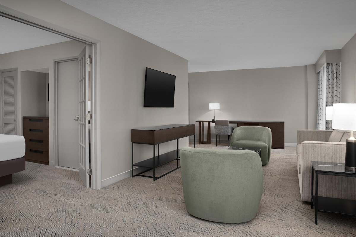 Una habitación de hotel con cama, escritorio, silla, sofá y televisión.