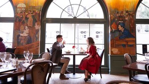 A restaurant with high arched windows and murals on the walls.