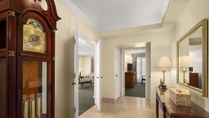 A hotel hallway with a grand wooden clock, a mirror, and a console table.