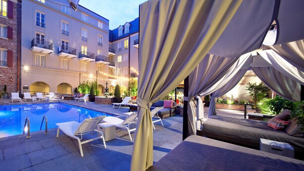 A pool area with lounge chairs and a covered seating area.