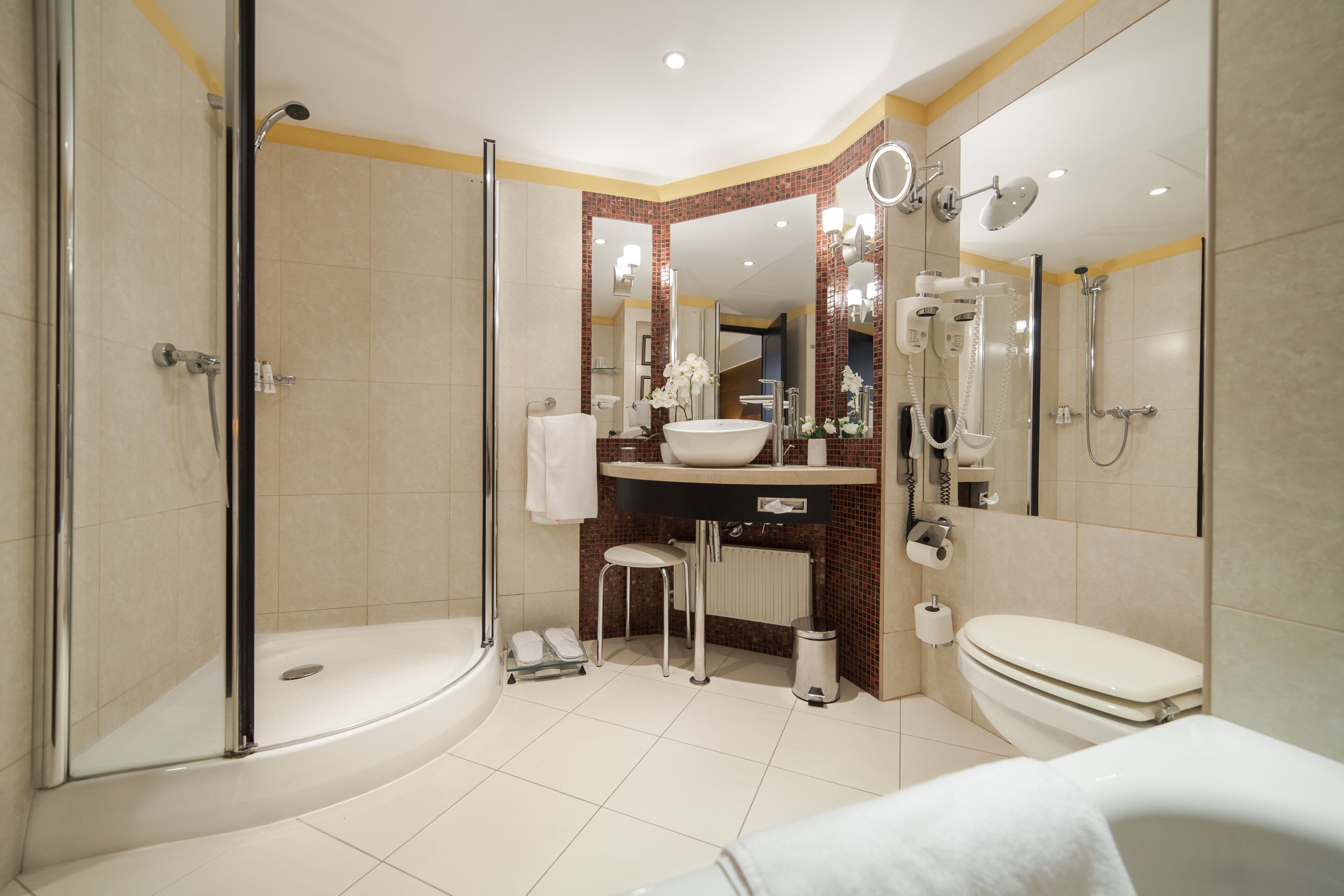 A modern bathroom with a glass-enclosed shower, a sink with a mirror, and a toilet.