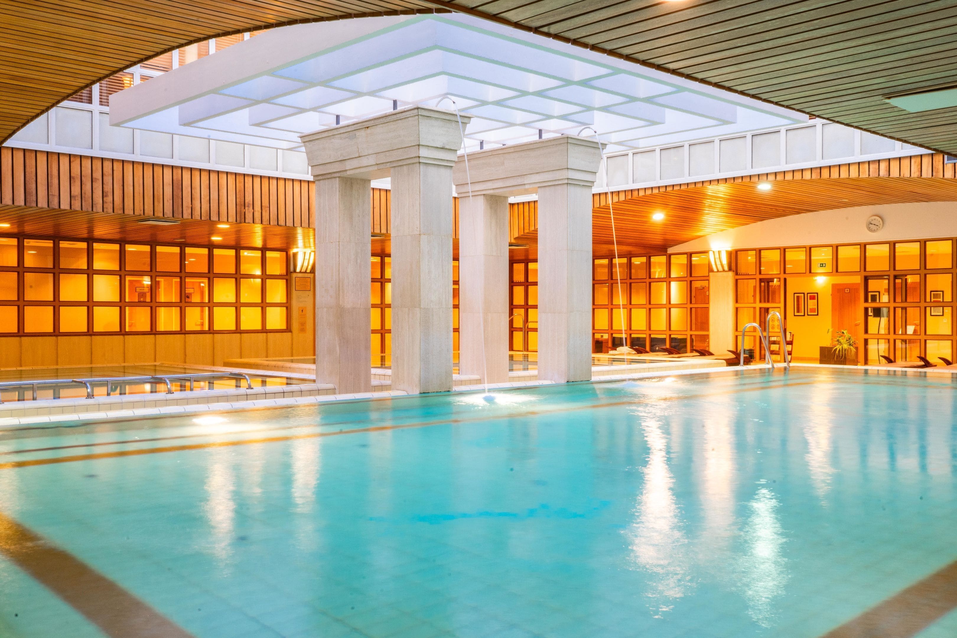 A large indoor swimming pool with a high ceiling and wooden paneling.