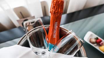 A champagne bottle in a metal bucket with glasses.