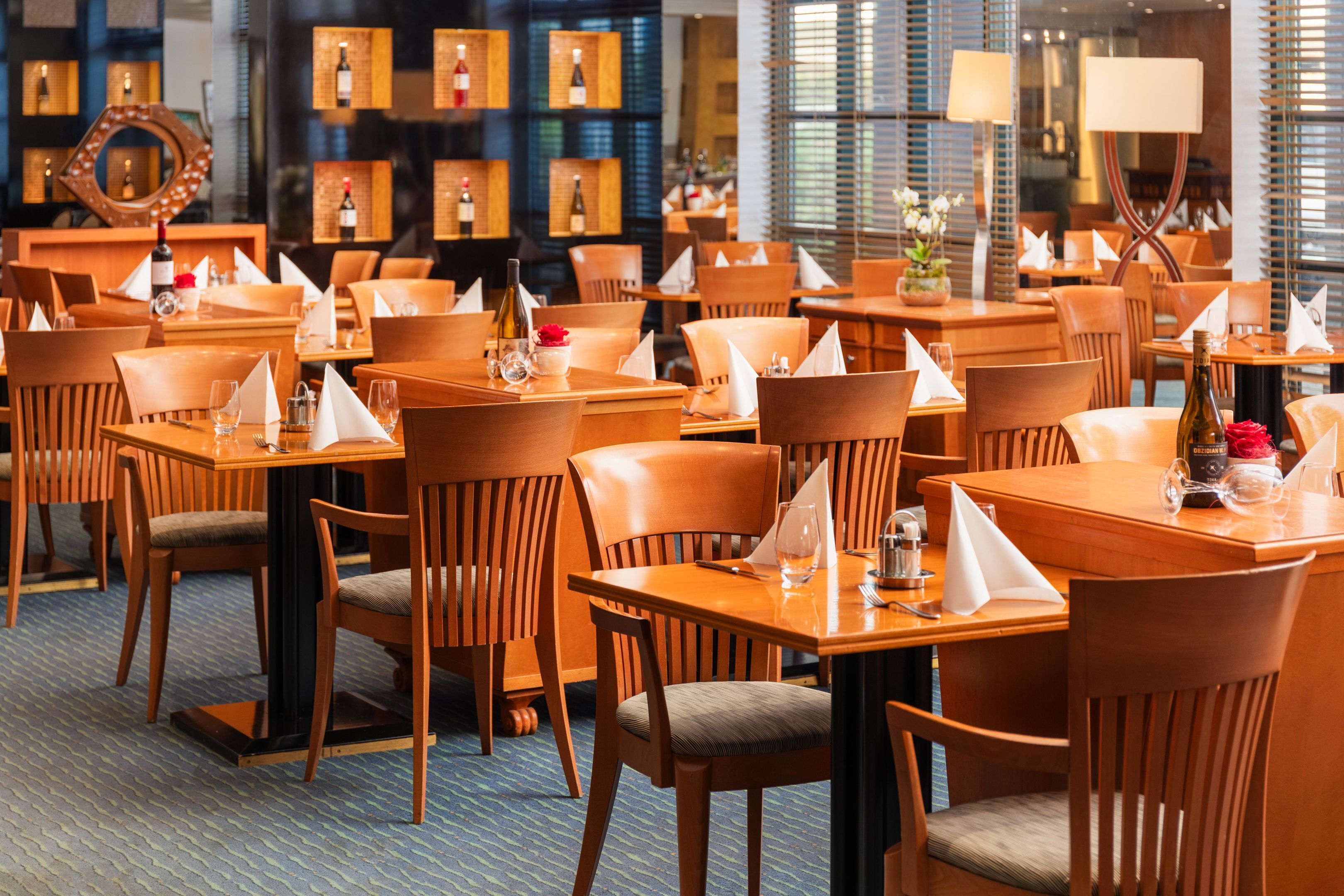 Un restaurante con varias mesas y sillas de madera, dispuesto en un espacio amplio.