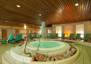 A pool area with a hot tub, lounge chairs, and a wooden ceiling. - Verdi Budapest Aquincum  (Budapest)