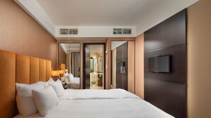 Una habitación de hotel con una cama grande, un televisor en la pared y un armario con espejo.