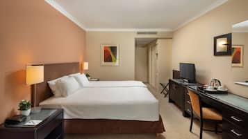Habitación de hotel con cama doble, escritorio con silla, televisor y lámpara de escritorio.