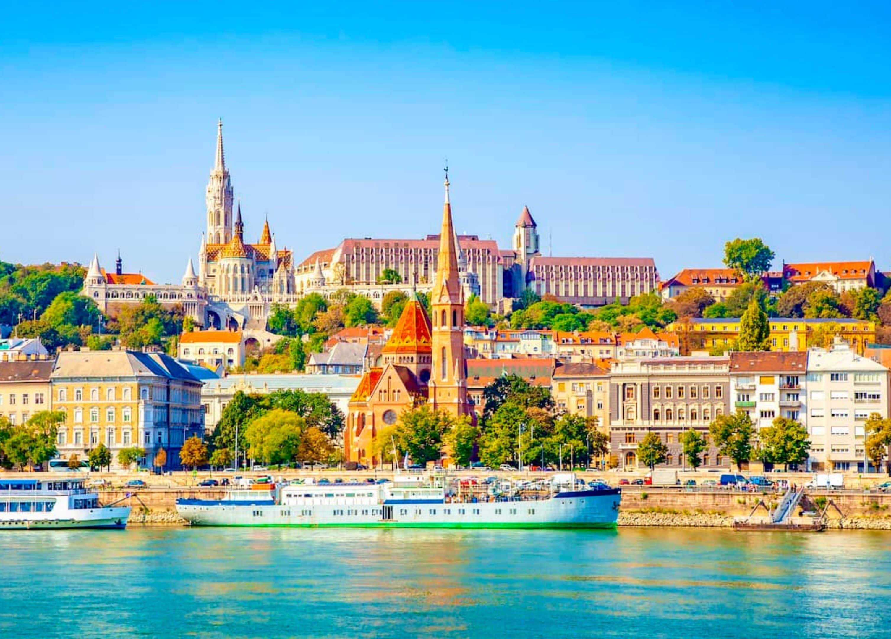 A river with a boat, buildings, and a prominent church with a tall spire.