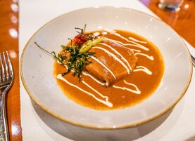 A plate of enchiladas with sauce and garnish on a white plate.