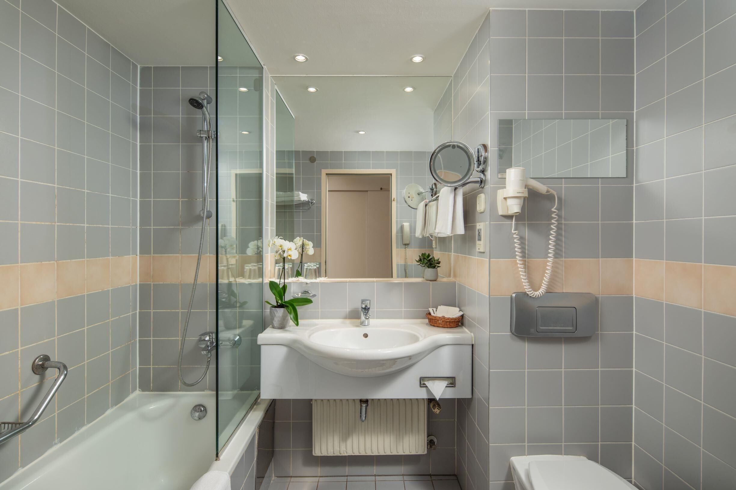 A modern bathroom with a glass-enclosed shower, a white sink, and a toilet.
