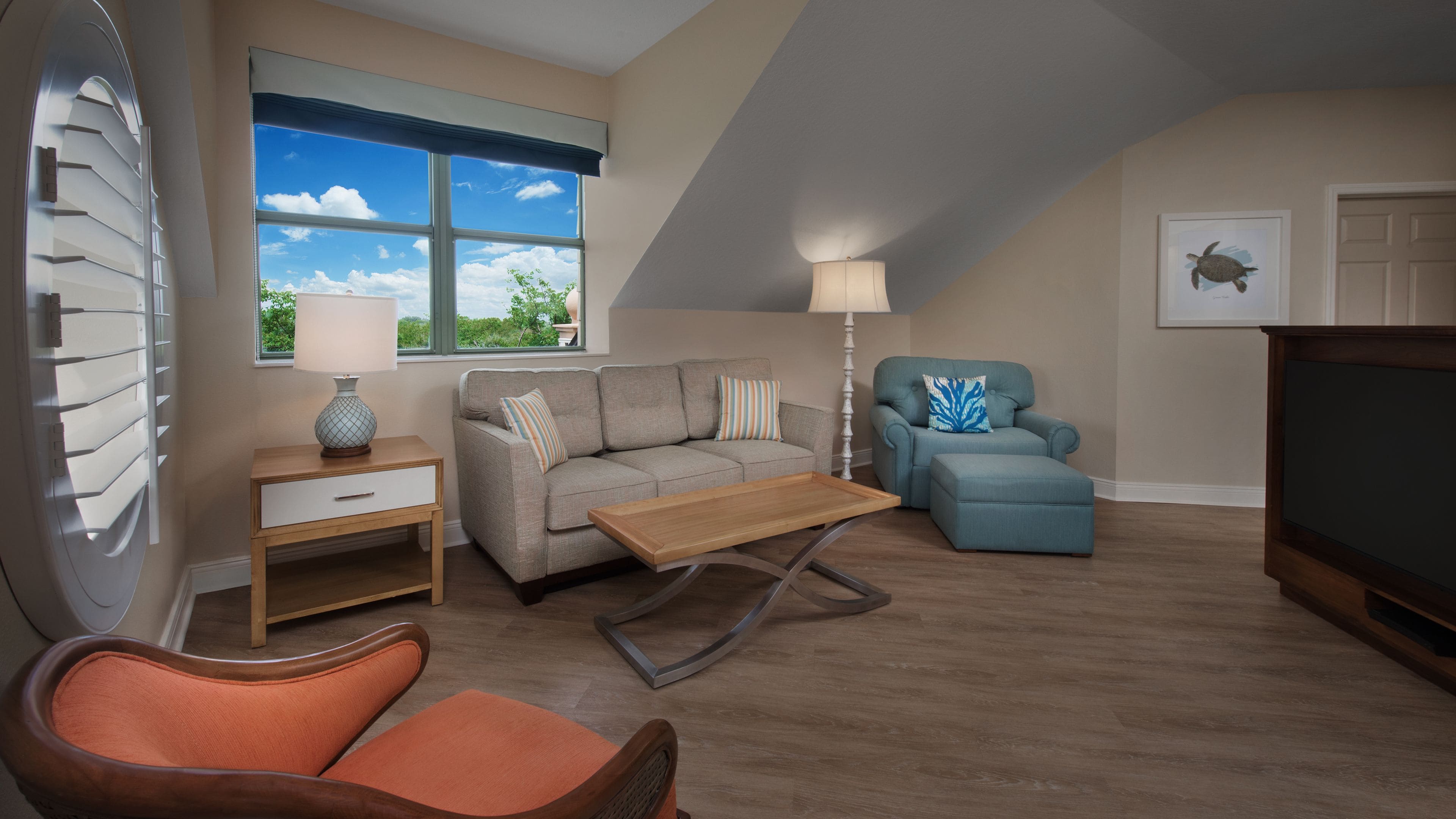 Una sala de estar con un sofá, un sillón, una mesita de centro, una lámpara y un televisor.