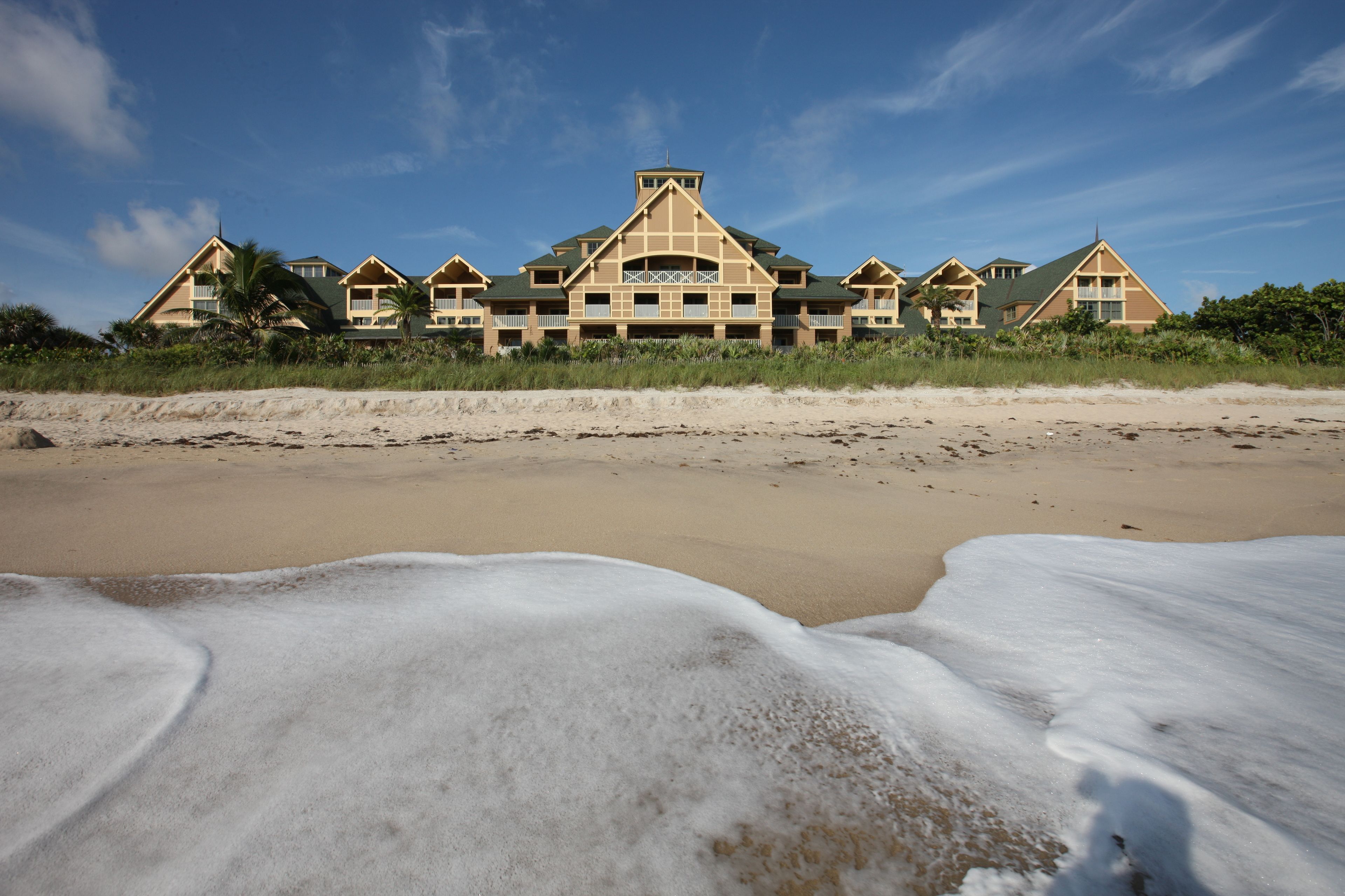 A beachfront hotel with multiple buildings, a sandy beach, and waves.