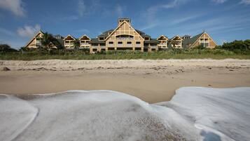A beachfront hotel with multiple buildings, a sandy beach, and waves.