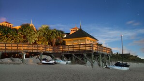 A beachfront property with a wooden deck, a building with a pointed roof, and two boats on the sand. - Disney's Vero Beach Resort (Vero Beach)