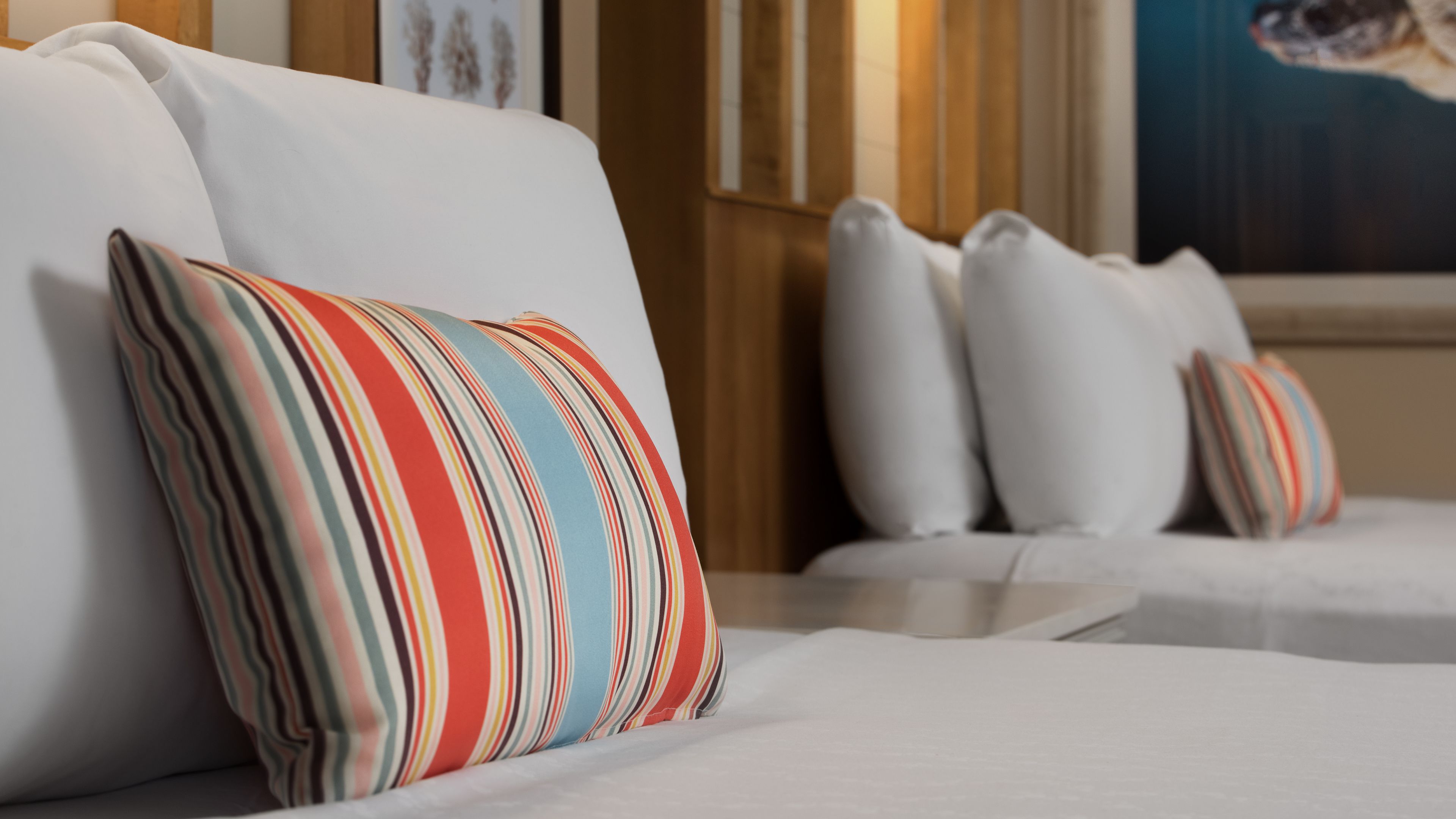Una camera d'albergo con un divano bianco e cuscini a righe.