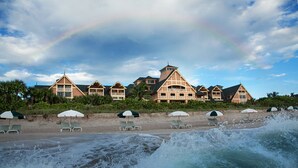 A beachfront hotel with multiple buildings, beach chairs, umbrellas, and a visible rainbow. - Disney's Vero Beach Resort (Vero Beach)