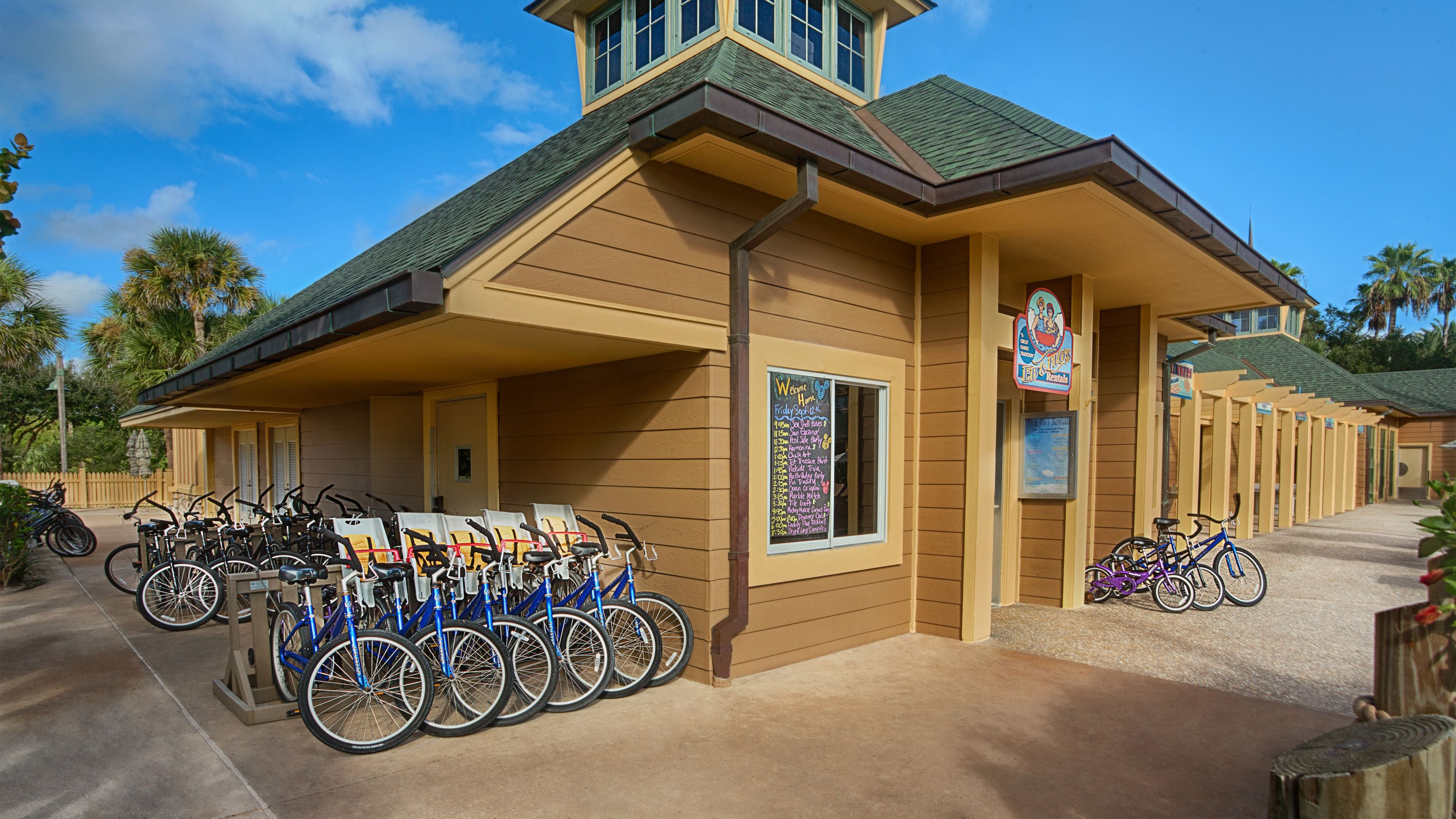 Un bâtiment à la façade marron et au toit vert, doté d’un panneau d’affichage contenant des informations sur la perte de poids et proposant un service de location de vélos.