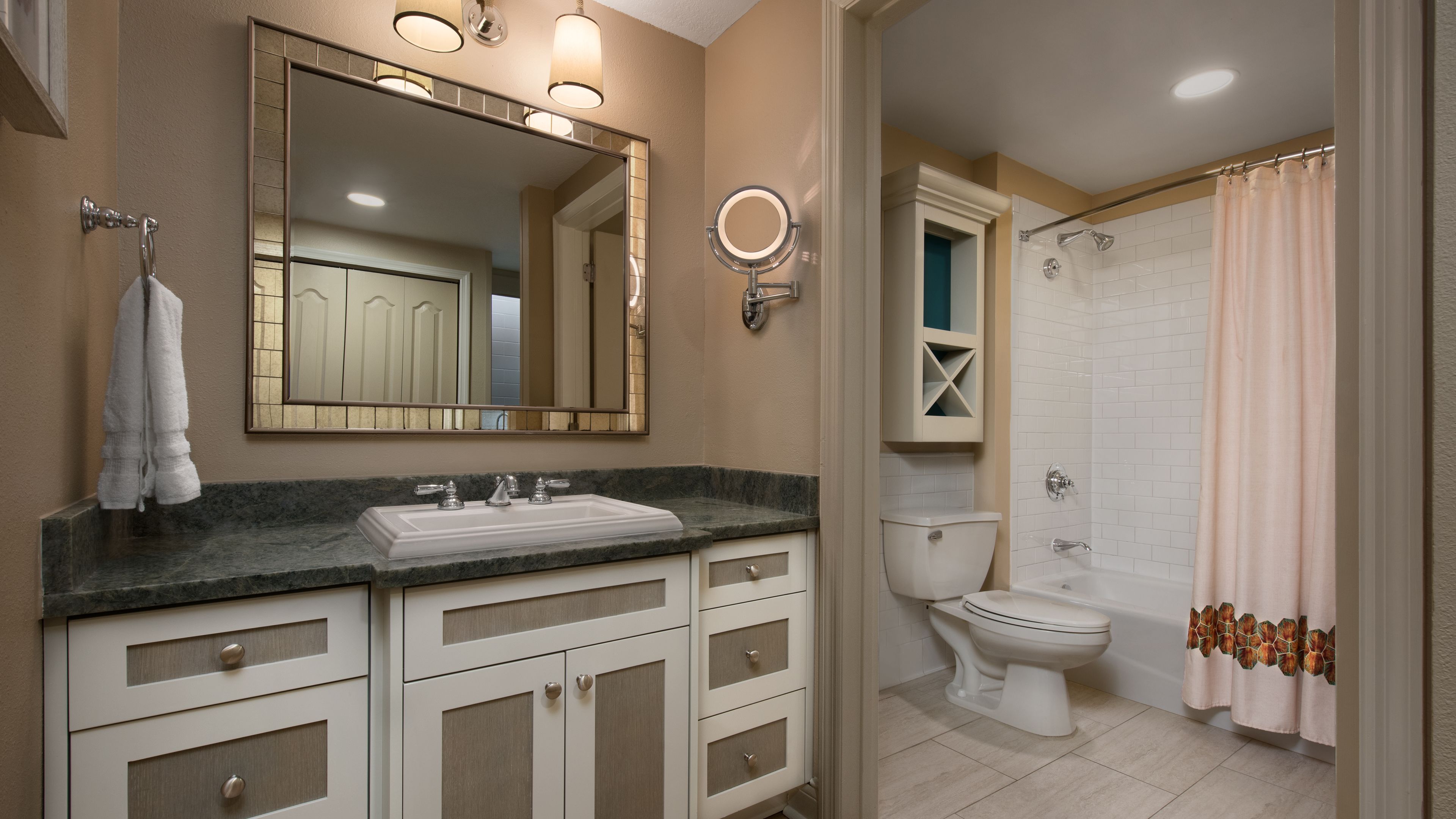 Une salle de bain équipée d’un lavabo, d’un miroir, de toilettes et d’un rideau de douche.