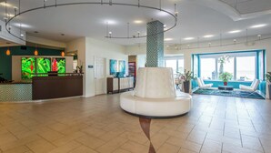 Un vestíbulo espacioso con una columna blanca central, una recepción y una zona de estar con vistas.