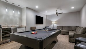 Una sala de estar moderna con billar, sofá y ventilador de techo.