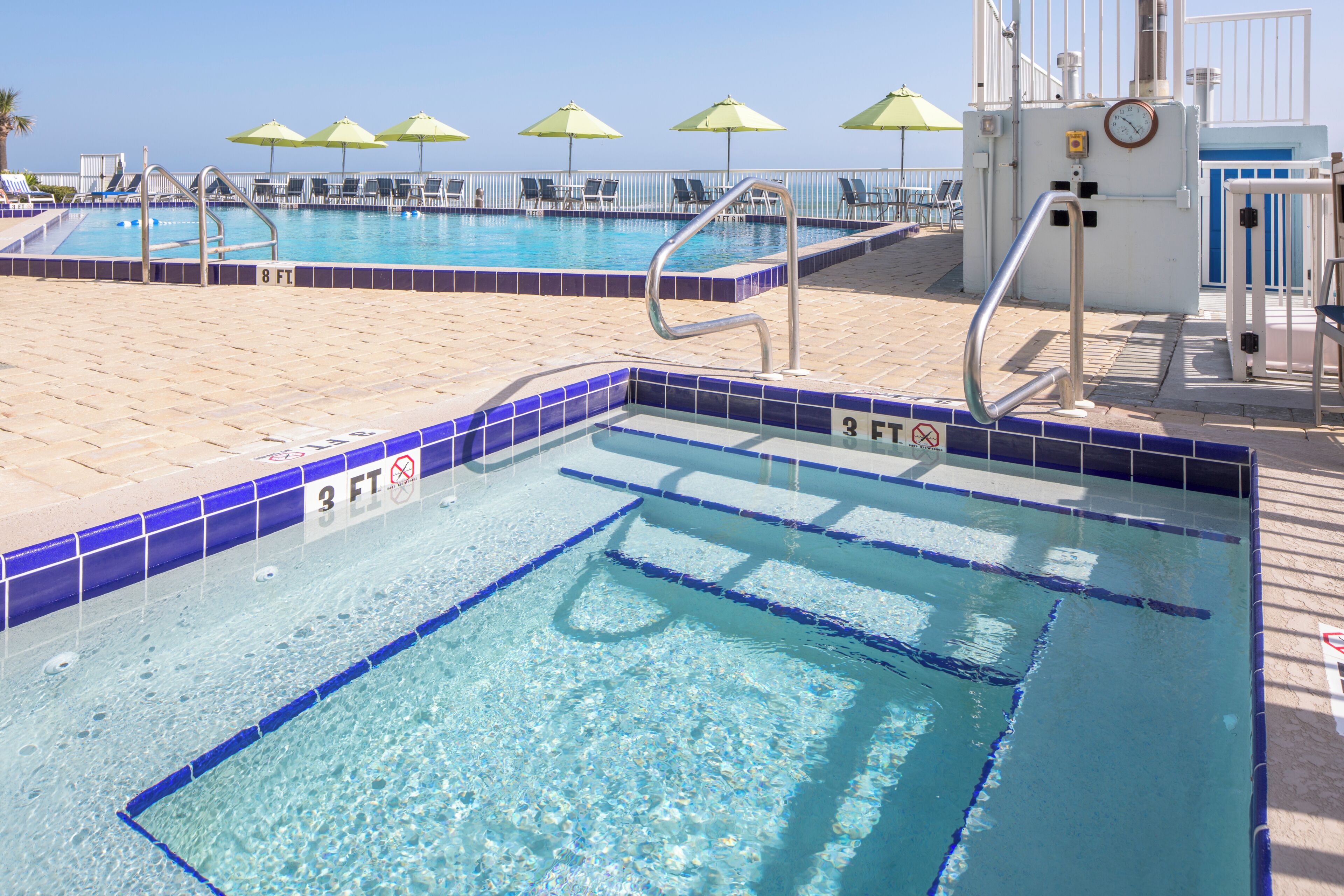 A pool area with multiple swimming pools, sun umbrellas, and lounge chairs.
