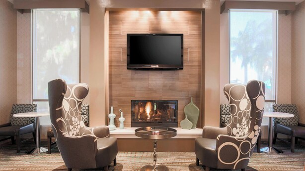A modern lounge area with two armchairs, a small round table, and a flat-screen TV mounted above a fireplace. - Residence Inn by Marriott Bakersfield (Bakersfield)