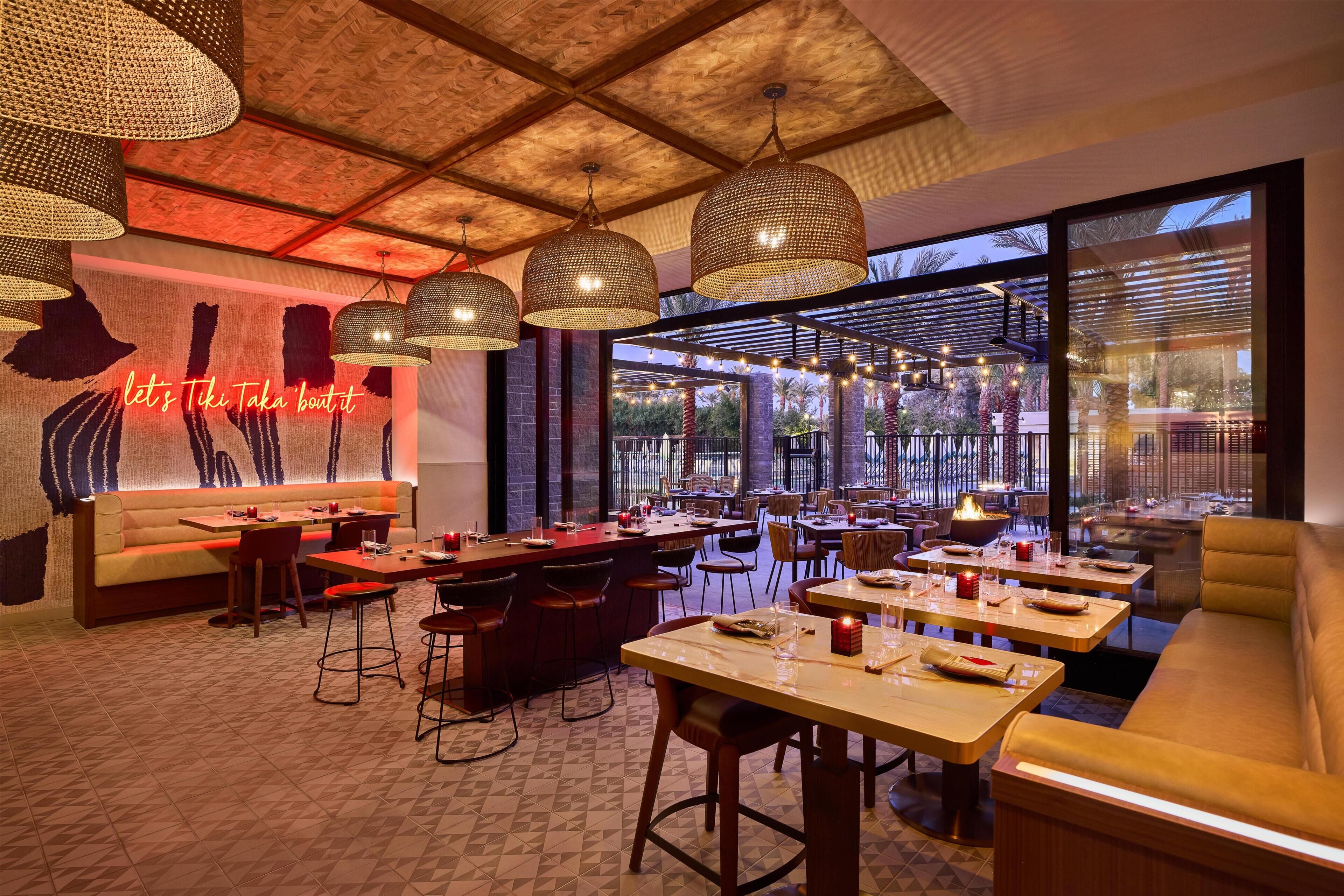 Un restaurante con un interior moderno, que cuenta con una zona de bar, distribuciones de asientos y grandes ventanales con vistas.